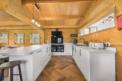 a kitchen with white cabinets and a wooden ceiling at Cabin in the countryside in Sible Hedingham