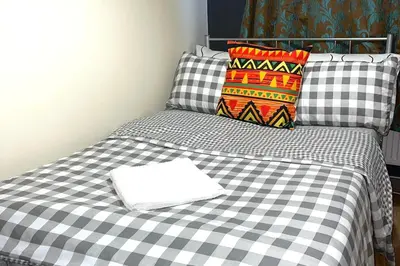 a bed with a black and white checkered blanket at House - Sleeps 10 - Garden - Parking in Romford