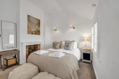 a white bedroom with two beds and a fireplace at Charming Church Walk, Long Melford - 2 bedroom property with parking in Long Melford