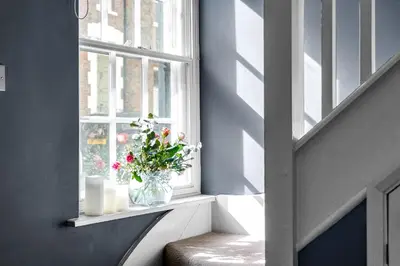 a window sill with a vase of flowers and candles at The Blue Anchor House - close to London in Hertford