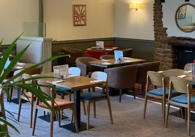 a restaurant with tables and chairs and a fireplace at Dragonfly Hotel Bury St Edmunds in Bury Saint Edmunds