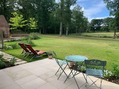 a patio with two chairs and a table in a yard at Private 2 Bedroom Apartment at Woodland Retreat in Gamlingay