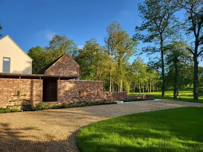a brick house with a gravel driveway at Private 2 Bedroom Apartment at Woodland Retreat in Gamlingay