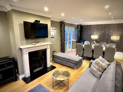 a living room with a couch and a fireplace with a table at Honey Hill Cottage - 4 Bedroom Detached House in Cambridge