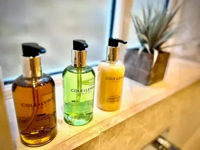 three bottles of soap sitting on a wooden shelf at Honey Hill Cottage - 4 Bedroom Detached House in Cambridge