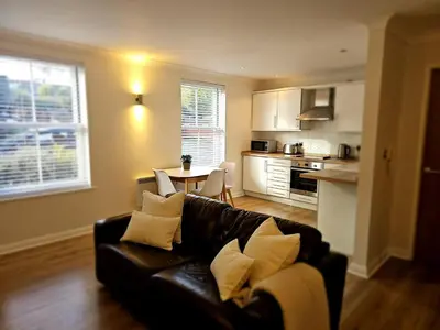 a living room with a black couch and a kitchen at Eaglegate in Colchester
