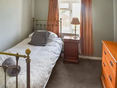 a bedroom with a bed and a dresser and a window at Heath View in Saxmundham