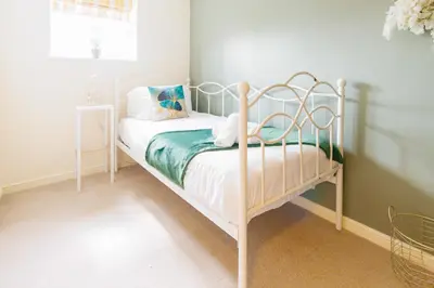 a small bedroom with a white bed with pillows at Cambridge 4 Bedroom Sleeps 9 Wi-Fi Garden, LONG STAYS ACCEPTED- Orchid House in Cambridge