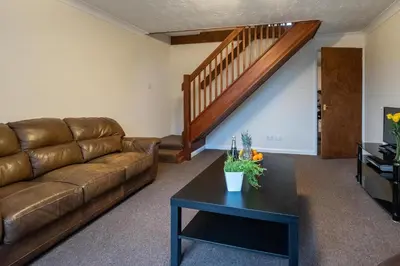 a living room with a brown couch and a table at 52 Carr Avenue in Leiston