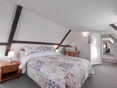 a bedroom with a large bed and a white wall at West House Farm in Leiston