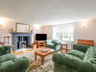 a living room with green furniture and a fireplace at West House Farm in Leiston