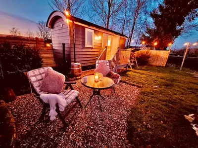 two chairs and a table in front of a house at Whiskers and Woods Shepherd Hut in Denham