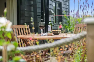 a table with a glass of wine and two chairs at Barn studio in Long Melford in Long Melford