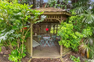 a wooden gazebo with a table and chairs in a garden at Barn studio in Long Melford in Long Melford