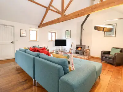 a blue couch in a living room with a fireplace at Packway Barn in Halesworth