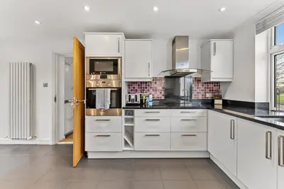 a kitchen with white cabinets and black counter tops at Boutique Cambridgeshire Gem in Fulbourn
