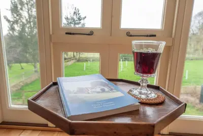 a tray with a book and a glass of wine at 3 Old School Cottages, Wissett in Halesworth