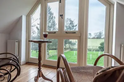 a dining room with windows and a table and chairs at 3 Old School Cottages, Wissett in Halesworth