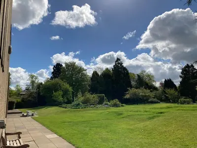 a green park with benches and a blue sky with clouds at Stephen Hawking Building Gonville and Caius College in Cambridge