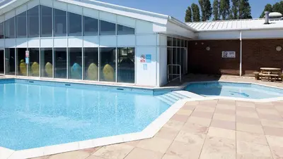 a swimming pool in front of a building at Lazeeedays on Mersea Island in Colchester
