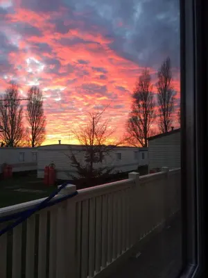 a sunset seen through a window with a fence at Lazeeedays on Mersea Island in Colchester