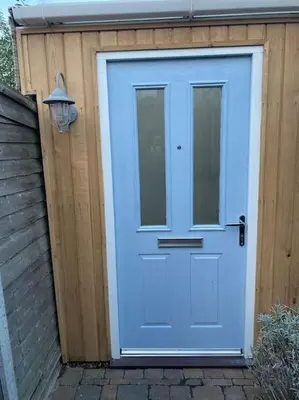 a blue door on a wooden building with a house at Shoreline hideaway - next to the beach in Holland-on-Sea