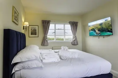 a white bed in a room with a window at Crows Hall in Colchester