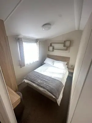 a small bedroom with a bed and a window at 4 Bed 10 Berth Caravan Seawick Holiday Park in Saint Osyth
