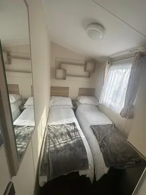a small bedroom with two beds and a window at 4 Bed 10 Berth Caravan Seawick Holiday Park in Saint Osyth