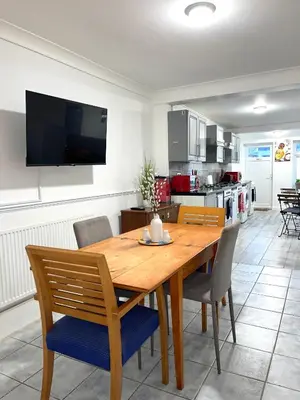 a dining room with a wooden table and chairs at Penn Gardens king size on suite room- 3 in Friern Barnet