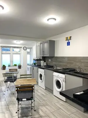 a kitchen with washing machines and a table and chairs at Penn Gardens king size on suite room- 3 in Friern Barnet
