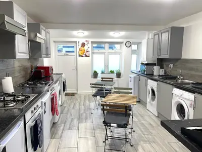 a kitchen with white appliances and tables and chairs at Penn Gardens king size on suite room- 3 in Friern Barnet