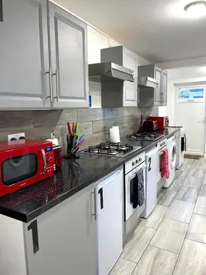 a kitchen with white cabinets and a red microwave at 12 Penn Gardens- Apart 2 in Friern Barnet
