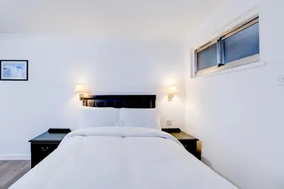 a bedroom with a white bed and two windows at The Rivenhall Hotel in Witham, Chelmsford in Witham