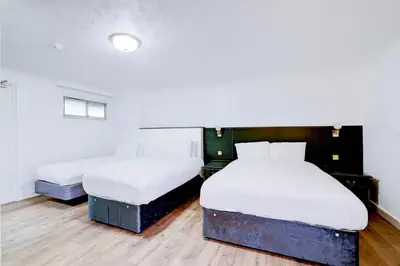 two beds in a room with wooden floors at The Rivenhall Hotel in Witham, Chelmsford in Witham