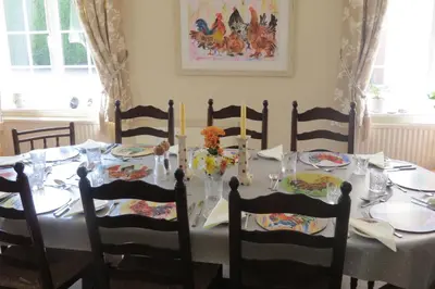 a dining room table with chairs and a table with candles at Newmans Lodge in Lavenham