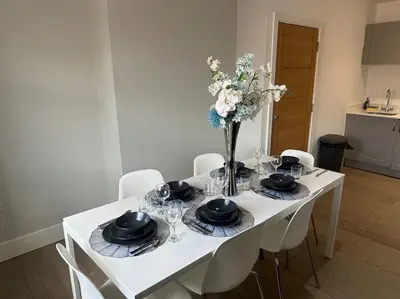a white table with chairs and a vase of flowers at Spacious, bright 2 bed flat with 1 S/king bed. in Brentwood
