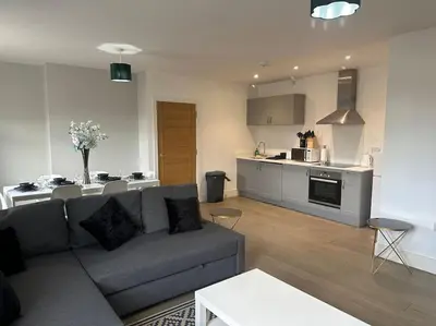 a living room with a couch and a kitchen at Spacious, bright 2 bed flat with 1 S/king bed. in Brentwood