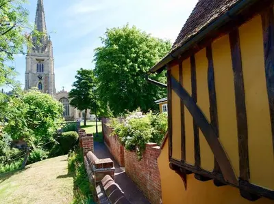 a building with a bench next to a church at The Famous Harry Potter House, Hot Tub, Cinema Room, Sky TV in Saffron Walden