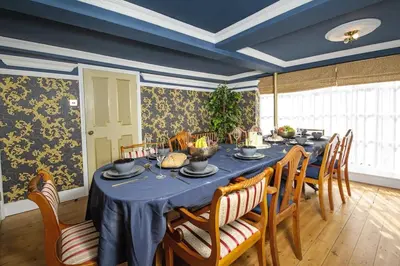 a dining room with a blue table and chairs at Luxury 2 Bed Manor House With Hot Tub, Cinema Room, Sky TV in Saffron Walden