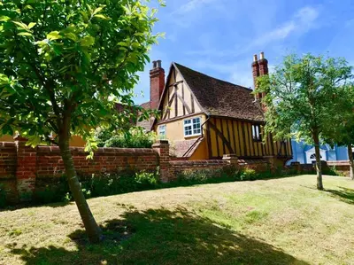 a house with a fence and a tree in front of it at Luxury 3 Bed Manor House With Hot Tub, Cinema Room, Sky TV in Saffron Walden