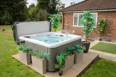 a hot tub in a yard with potted plants at Deluxe 1 Bed Versace Hot Tub Sky TV Cinema Screen in Great Sampford