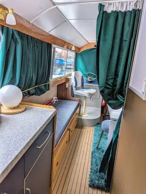 a small room with a kitchen with green curtains at New Horizon - A beautiful boat very conveniently located in Chelmsford City in Chelmsford