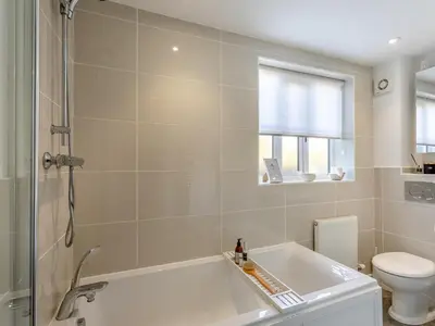 a bathroom with a bath tub and a toilet at Malting Cottage in Much Hadham