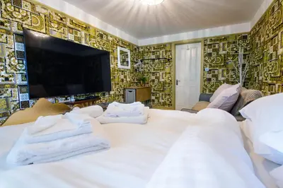 a bedroom with a large white bed and a tv at Deluxe 2 Bed Versace HotTub SkyTV in Saffron Walden