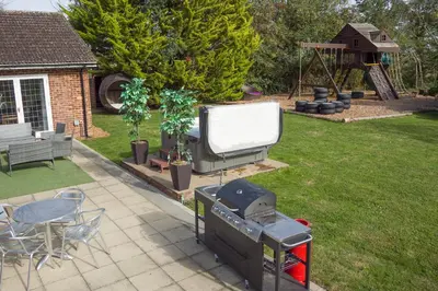 a backyard with a big screen tv and a grill at Deluxe 2 Bed Versace HotTub SkyTV in Saffron Walden