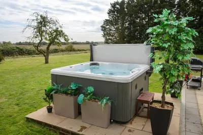 a hot tub in a garden with two potted plants at Deluxe 2 Bed Versace HotTub SkyTV in Saffron Walden