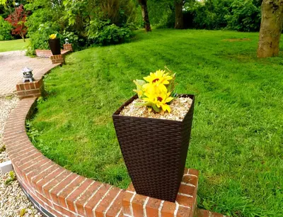 a planter with a yellow flower on a brick path at Deluxe 2 Bed Versace HotTub SkyTV in Saffron Walden