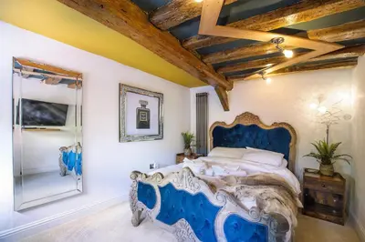 a bedroom with a blue bed and a mirror at Executive Suite with Private Hot Tub SkyTV in Saffron Walden