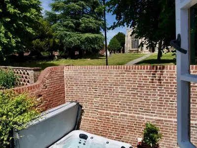 a brick wall with a bath tub in a yard at Executive Suite with Private Hot Tub SkyTV in Saffron Walden